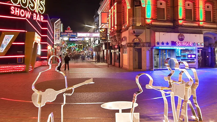 Neon-lit street with metal band sculptures.