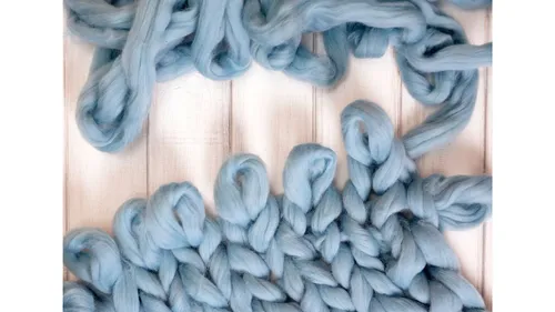 Blue yarn knitted on wooden table.