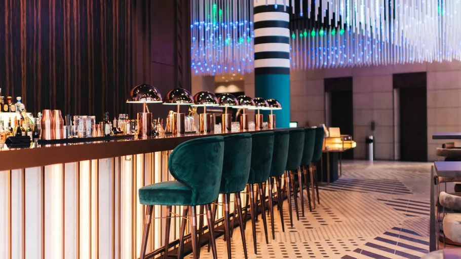Moderne Bar mit grünen Hockern und Beleuchtung.