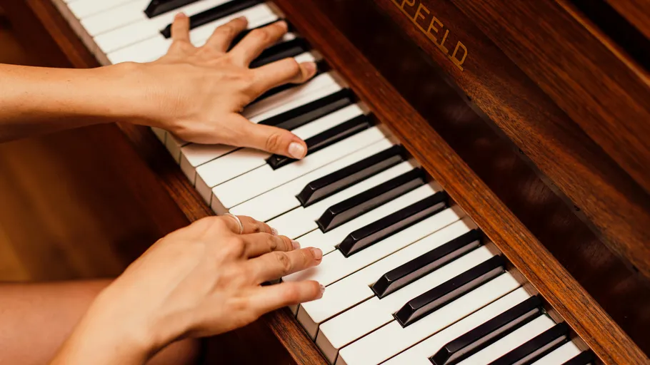 Hands playing piano keys indoors.