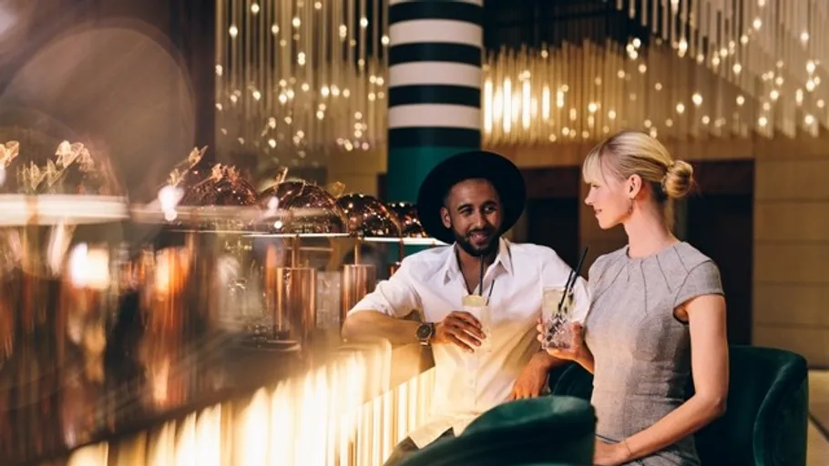 Zwei Personen unterhalten sich an stilvoller Bar.