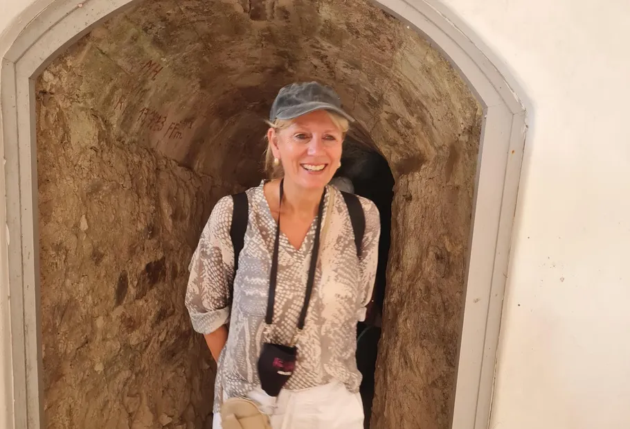 Frau lächelt, steht in antikem Steinbogen.