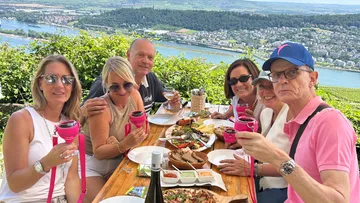 Gruppe genießt Mahlzeit mit Flussblick.