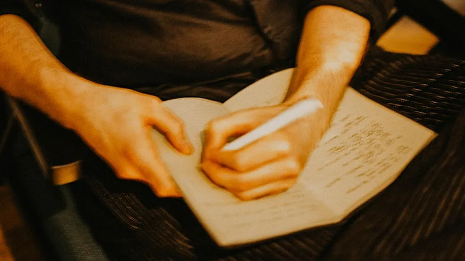 Person writing in notebook indoors.