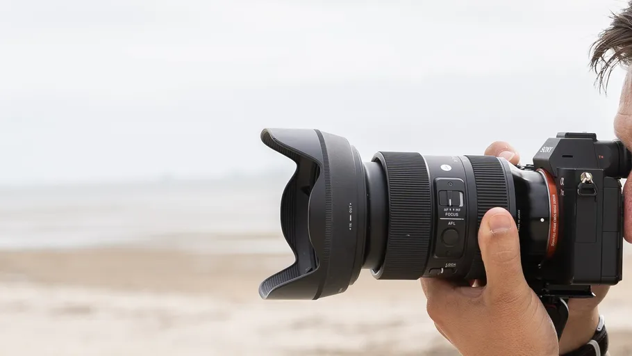 Person photographing beach with DSLR camera.