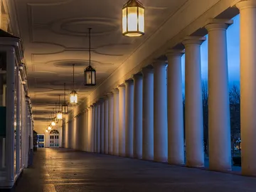 Pillars stand under a lantern-lit, shady covered area.