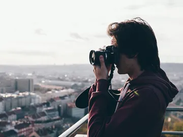 Junger Mann fotografiert die Stadt von einem Aussichtspunkt.