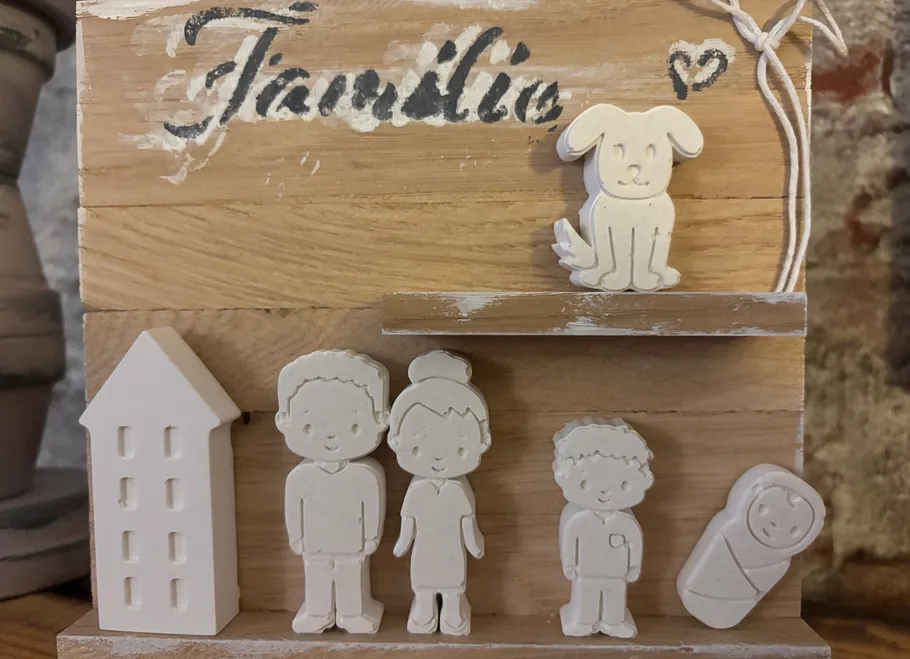 Clay family figurines on wooden shelf display.