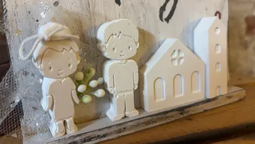 Tonfiguren eines Paares neben Kirchenmodell.