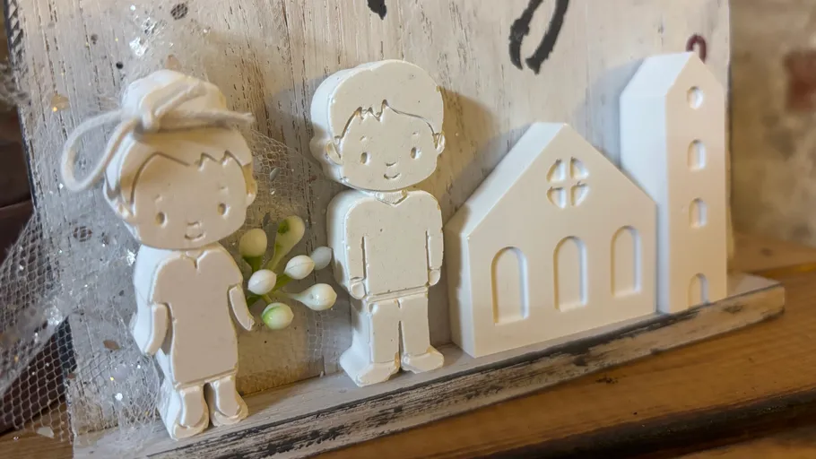 Clay figures of couple beside church model.