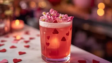 Rosa Cocktail mit Blumen und Herzen dekoriert.