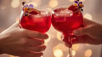 Two glasses of red cocktails clinking together.