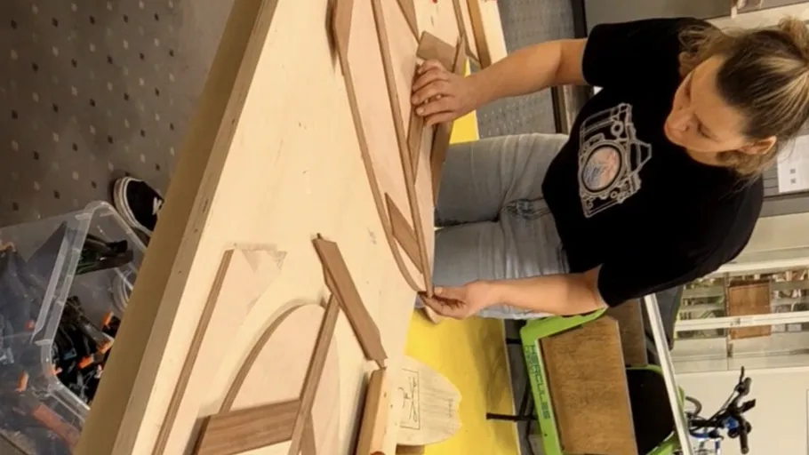 Person bearbeitet Holzteile auf einer Werkbank.