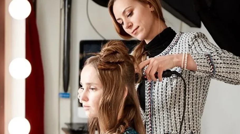 Woman styling another woman's hair indoors.