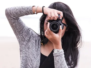 Eine Person fotografiert am Strand mit einer Kamera.