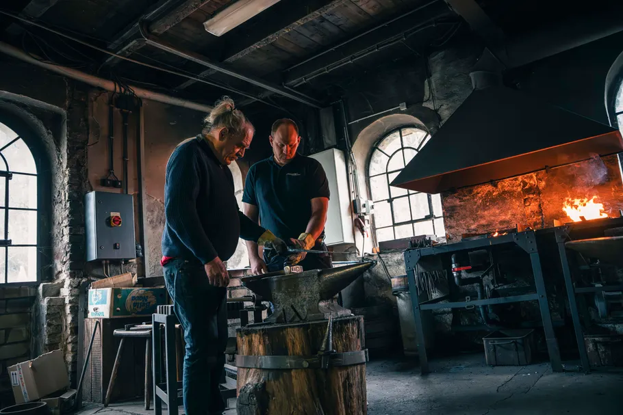 Two blacksmiths working in a forge.