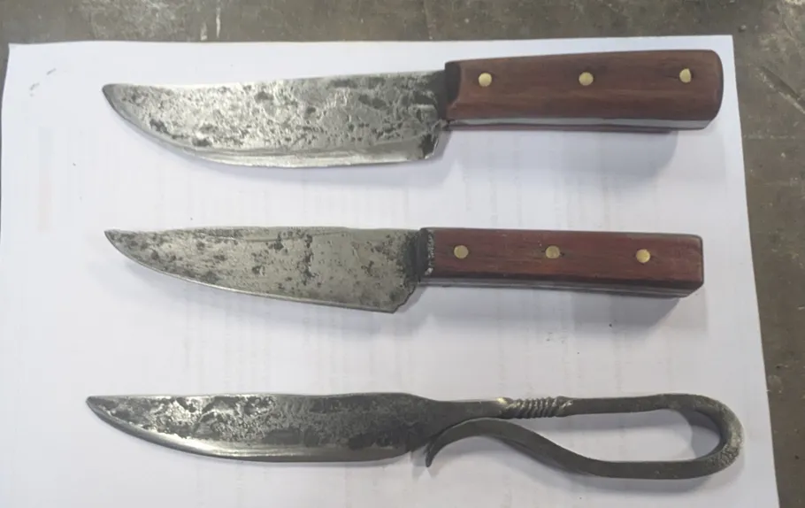 Three rustic knives on a white surface.