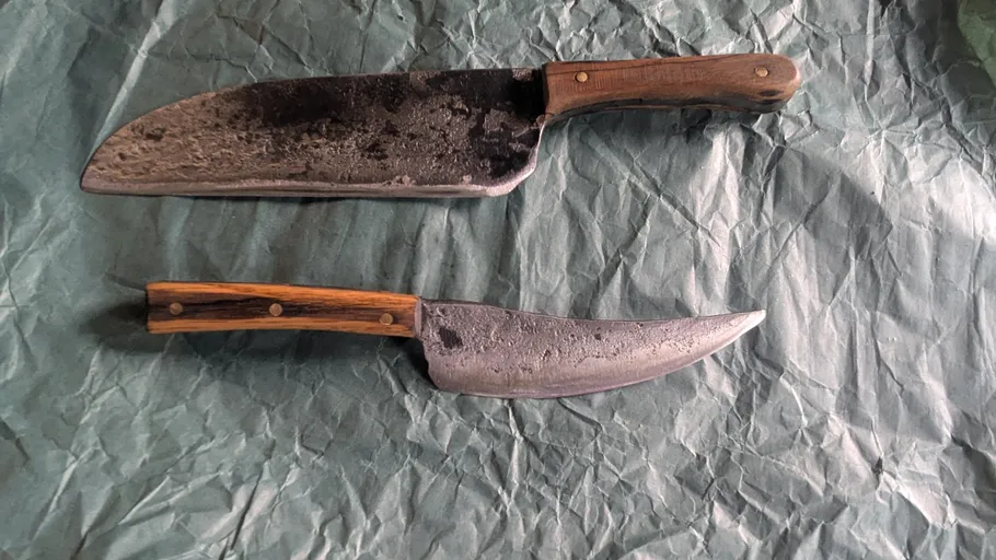 Zwei rustikale Messer auf zerknittertem Stoff.