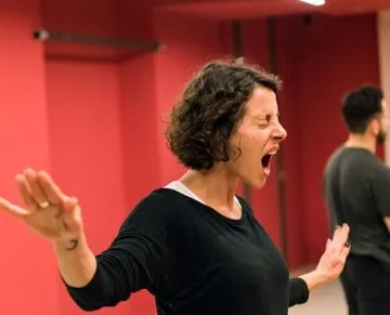 Woman energetically shouting in a red room.