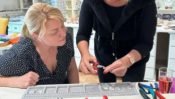 Two people making jewelry with pliers.