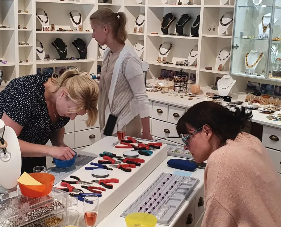 Three people making jewelry in a store.