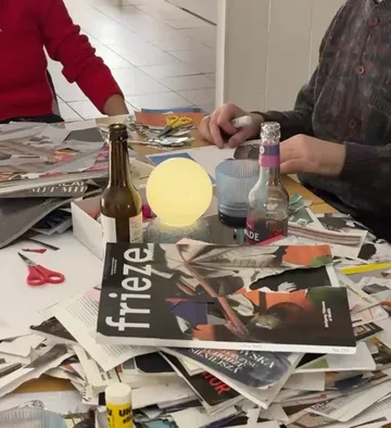 Menschen basteln mit Zeitschriften auf Tisch.