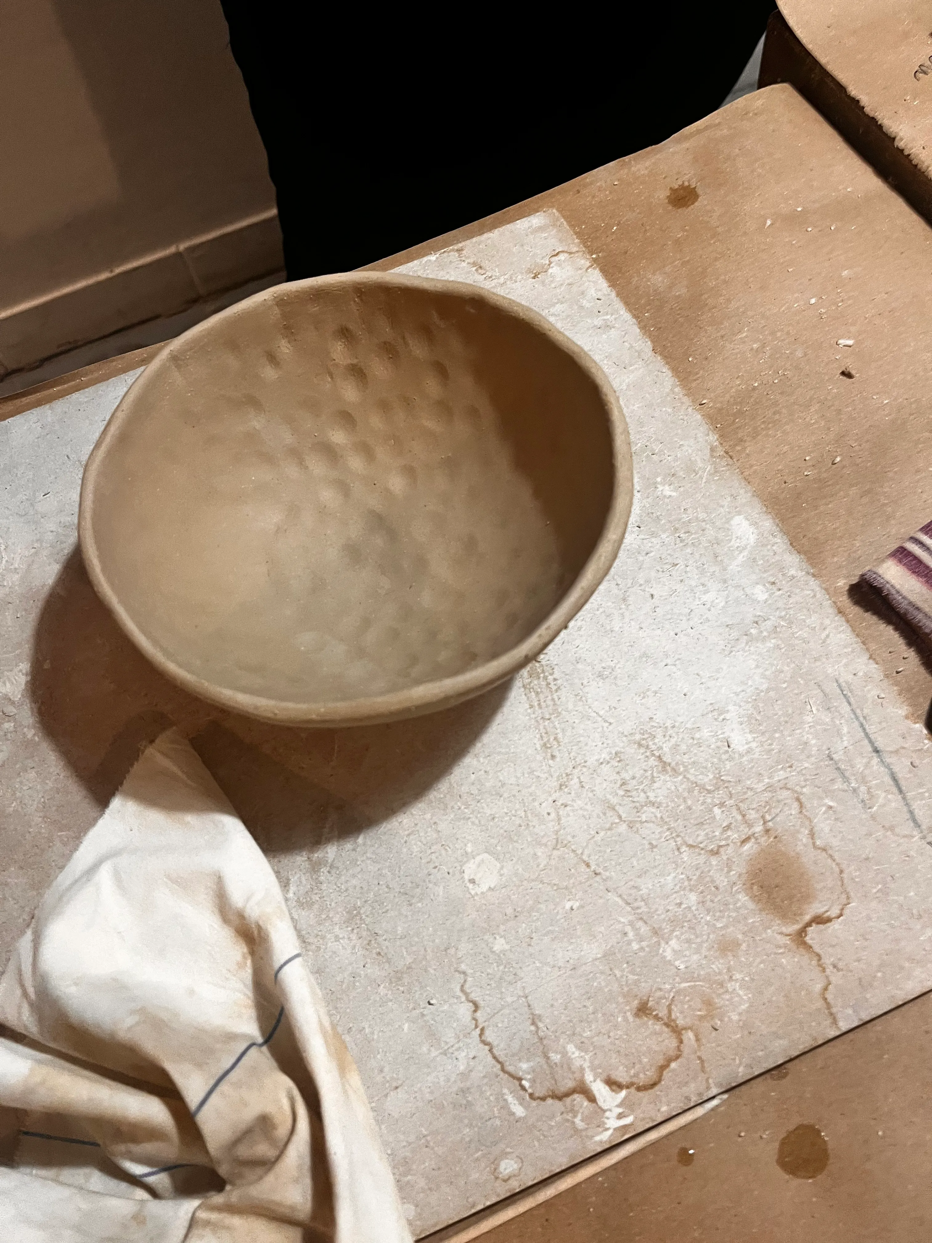 Clay bowl on messy workshop table.