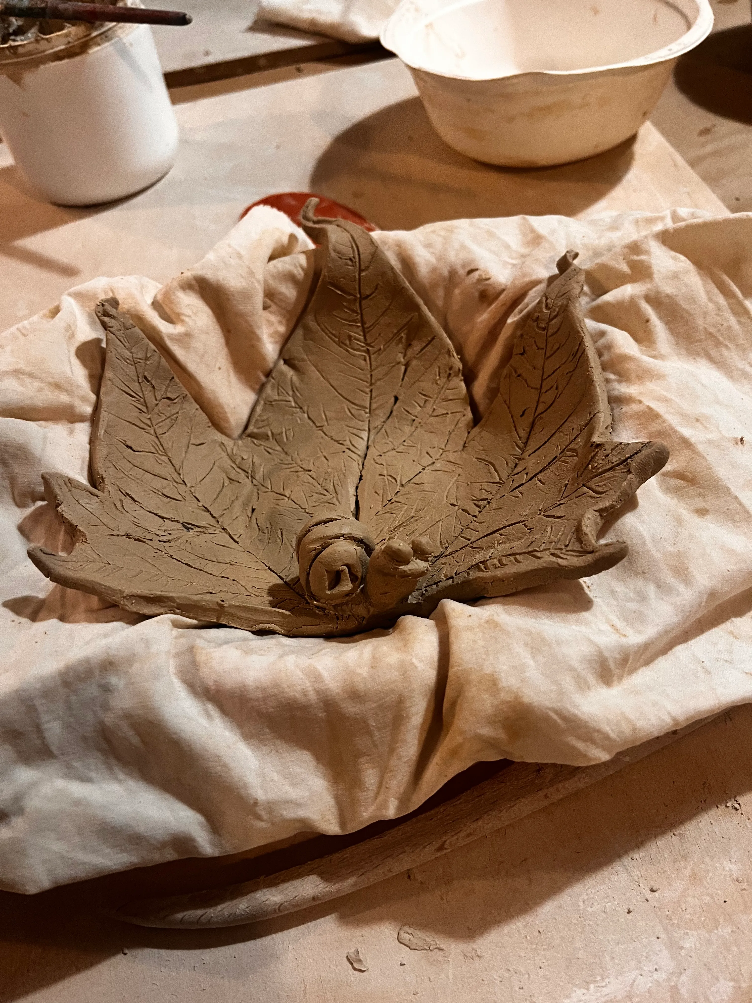Clay leaf sculpture drying on fabric.