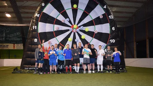 Gruppe posiert vor riesiger Dartscheibe.