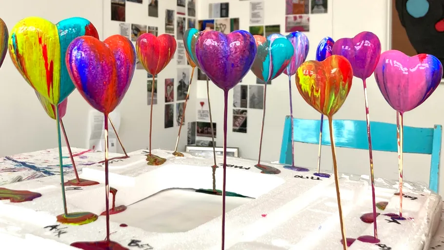 Colorful heart-shaped sculptures dripping paint in studio.