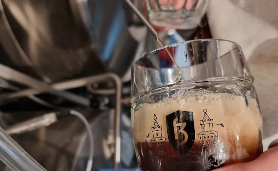 Beer glass filling with dark beer in brewery.