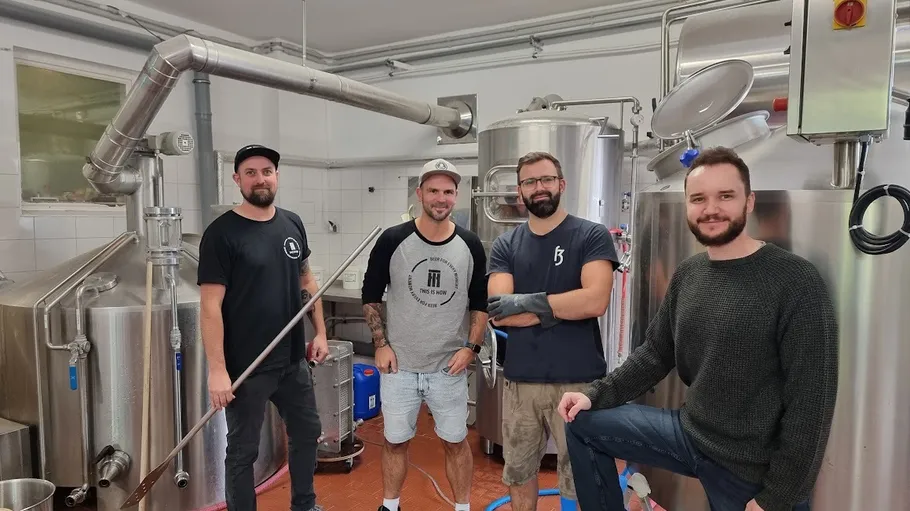 Vier Männer stehen in Brauerei mit Geräten.