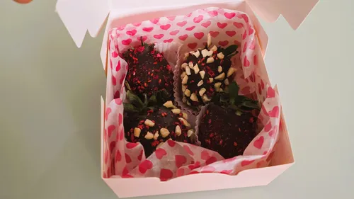 Schachtel mit schokolierten Erdbeeren und Nüssen.