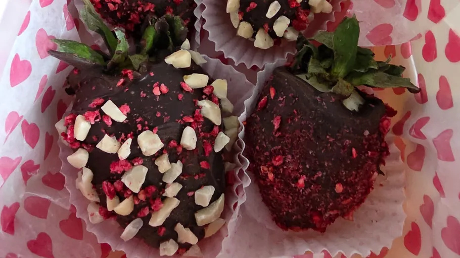 Strawberries coated in chocolate, sprinkled with nuts.