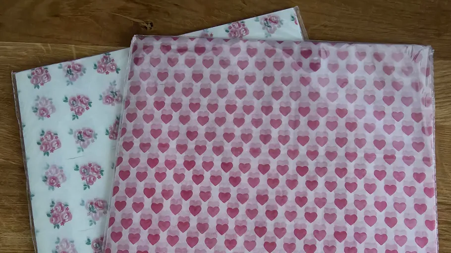 Heart and floral patterned sheets on table.