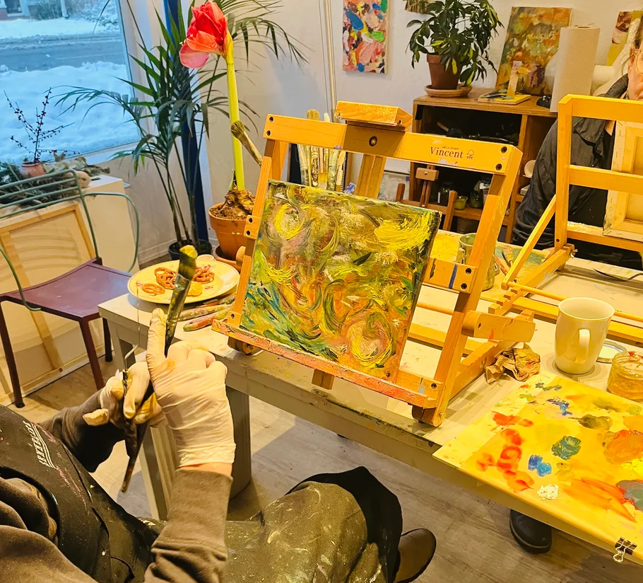 Person painting on canvas with vibrant colors indoors.