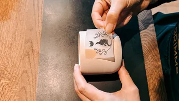 Person applying sticker to a ceramic mug.