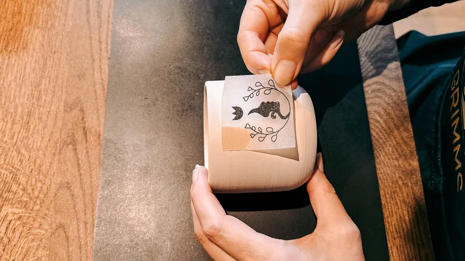 Person klebt Aufkleber auf eine Keramiktasse.