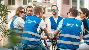 People in blue vests sitting outdoors biking.