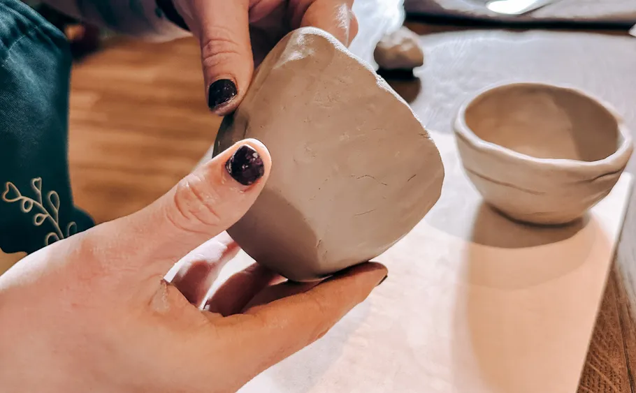 Hands shaping pottery in a workshop.