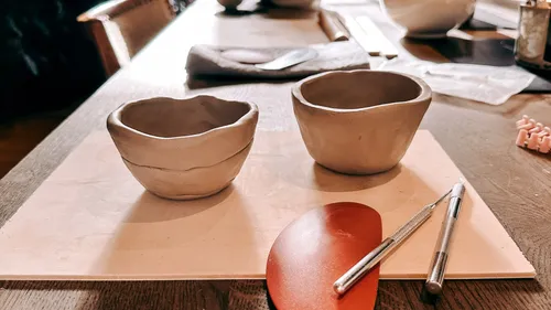 Two clay bowls on a wooden table workspace.