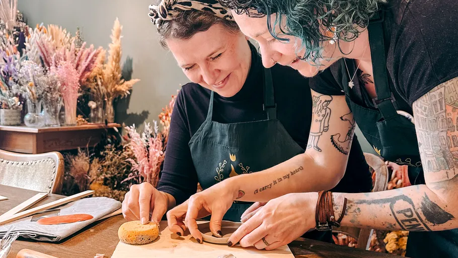Two people crafting ceramics at wooden table.