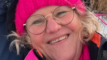 Frau lächelt, trägt pinke Winterkleidung.