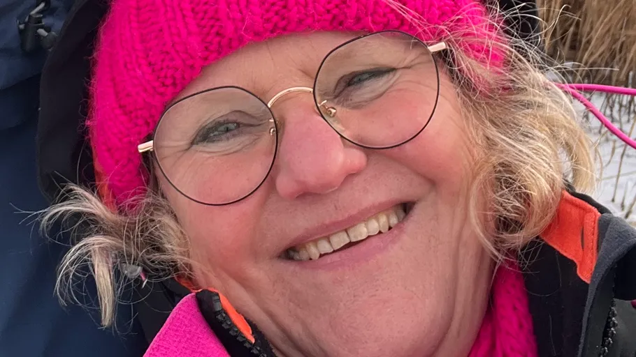 Frau lächelt, trägt pinke Winterkleidung.