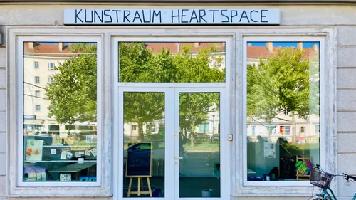 Kunstgalerie mit großen Fenstern und Schild.