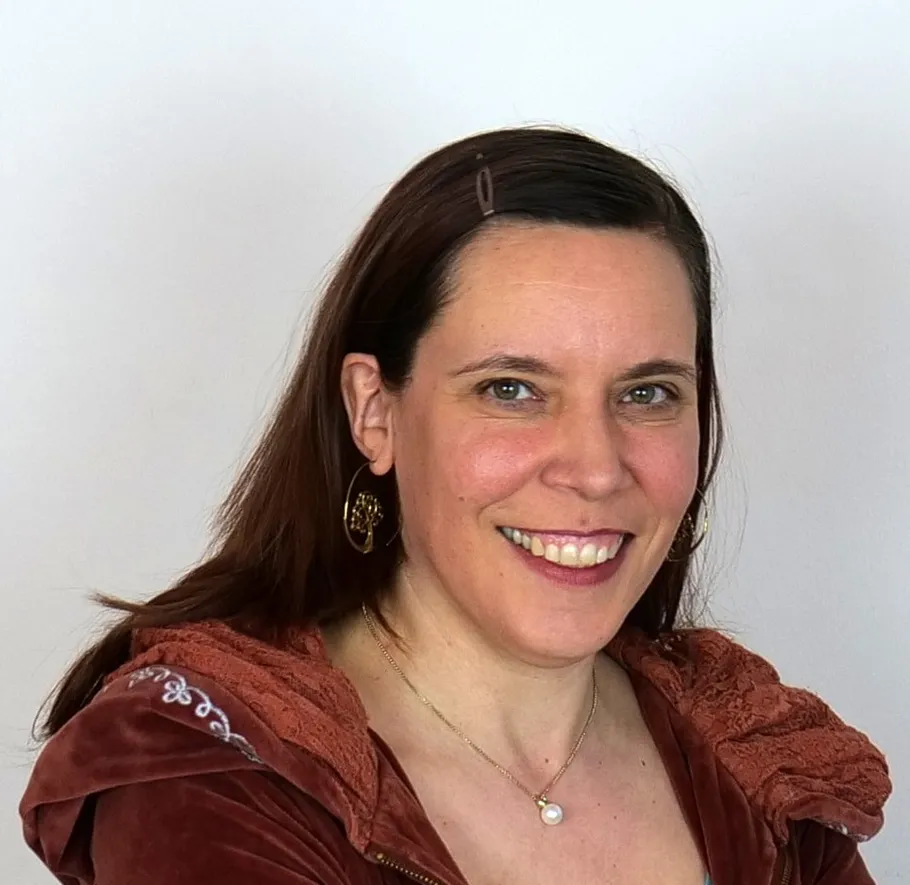 Smiling woman wearing brown jacket indoors.