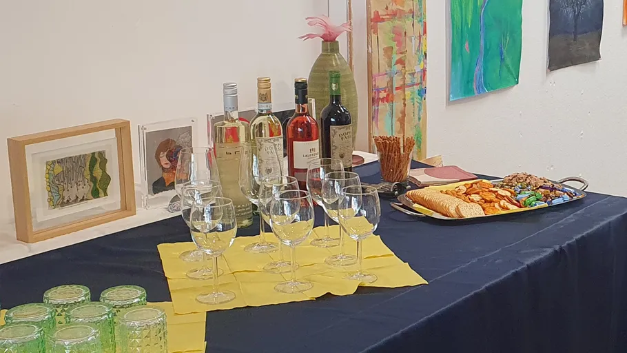 Wein und Snacks auf Tisch in Kunstgalerie.