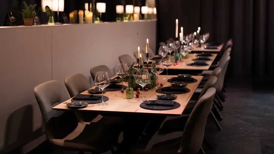 Eleganter Tisch mit Kerzen und grüner Dekoration.