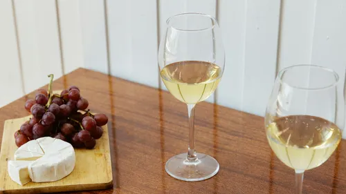 Two wine glasses with cheese and grapes nearby.