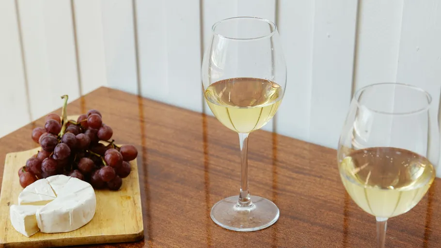 Two wine glasses with cheese and grapes nearby.